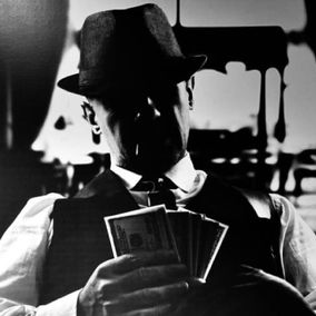 Mustavalkokuva pokeria pelaavasta miehestä klassisessa puvussa